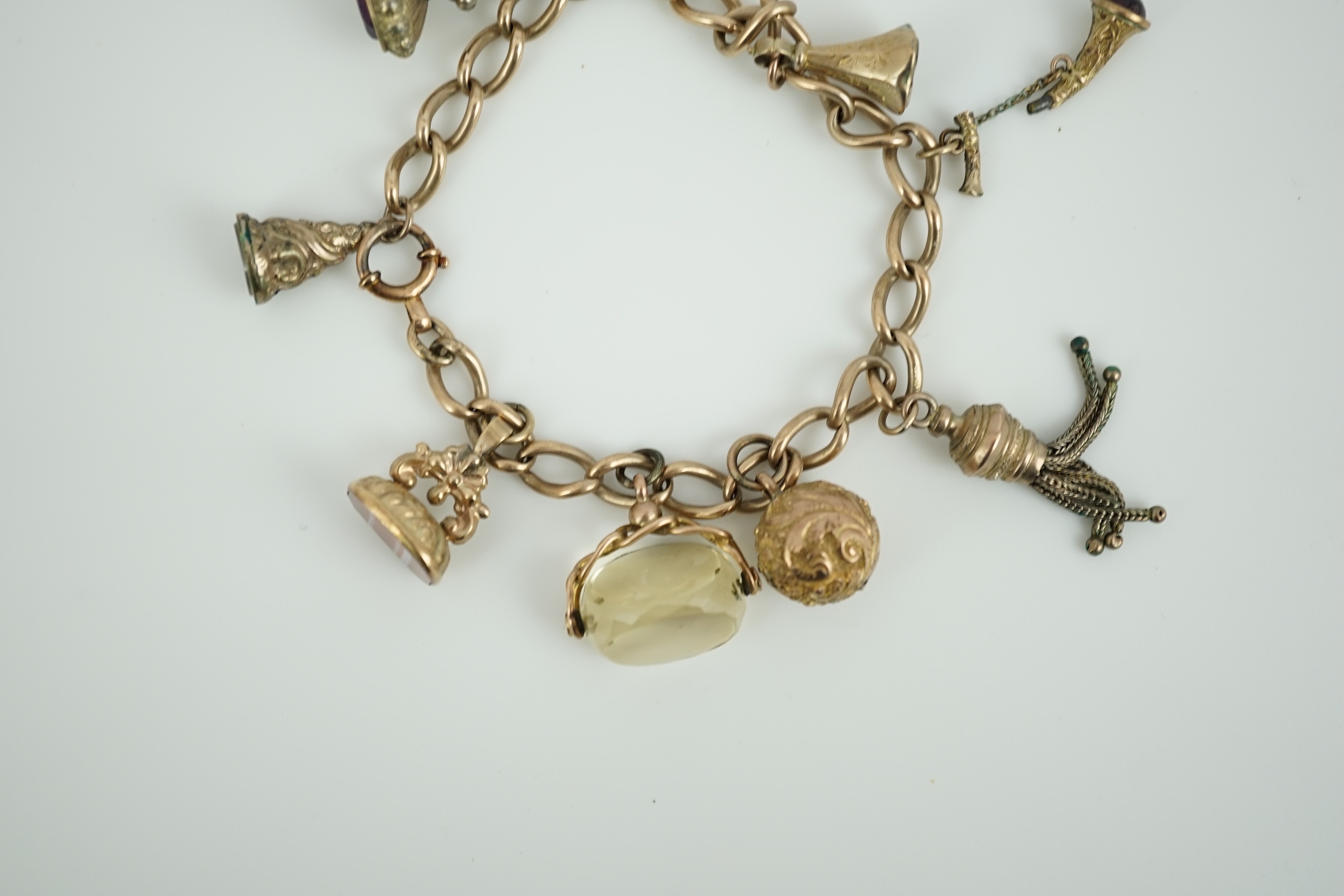 A 9ct gold charm bracelet, hung with eight assorted yellow metal overlaid charms, gross weight 33.4 grams.